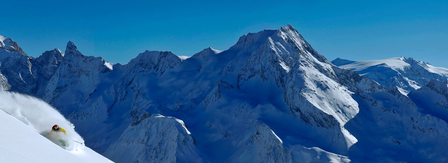 A skier in powder snow in front of a mountain range